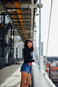 Smiling young woman looking away while leaning on railing