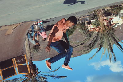 Tilt image of young man practicing stunt at skateboard park