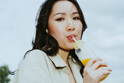 Portrait of young woman drinking juice from bottle