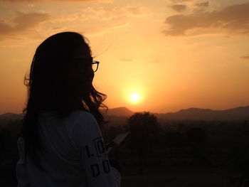 Rear view of woman standing against orange sky