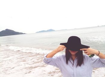 Woman in sun hat at beach against clear sky