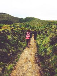 Rear view of people walking on mountain against sky