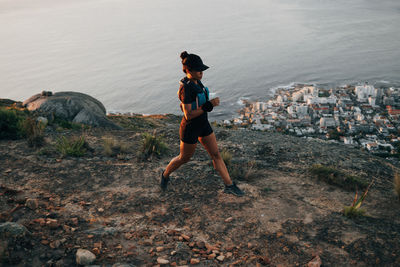 Full length of woman running on mountain cliff