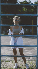 Full length portrait of woman standing against railing