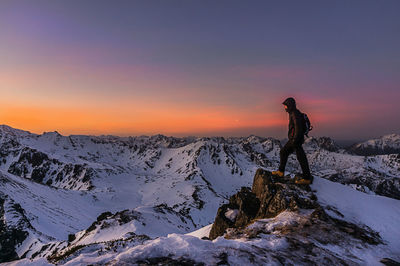 Man in snow on landscape against sky during sunset
