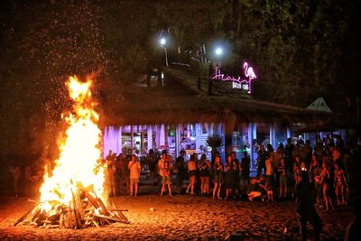 People by illuminated bonfire at night