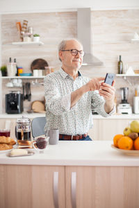 Senior man holding mobile phone at home