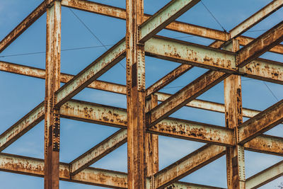 Low angle view of rusty metallic structure against sky