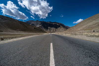 Empty road amidst desert against sky