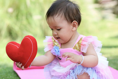 Cute girl holding heart shape outdoors