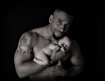 Man holding baby against black background