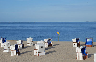 Deck chairs on beach against sky