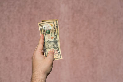 Close-up of hand holding paper against wall