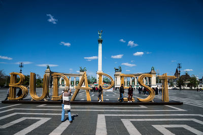 Text and millennium monument against sky at hero square in city