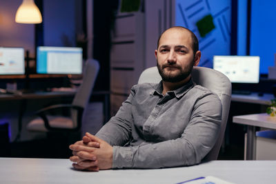 Portrait of young man using laptop at desk in office