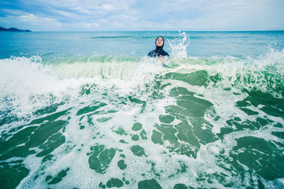 Boy enjoying in sea against sky