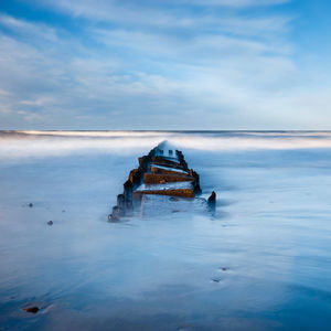 Abandoned boat in sea against sky during winter