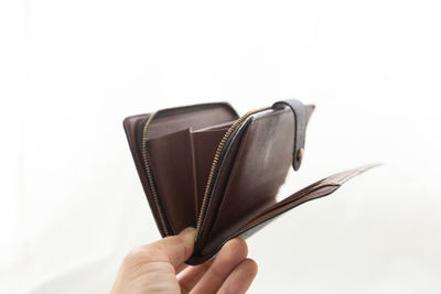 Close-up of hand holding book against white background