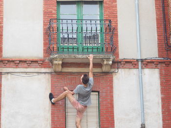 Rear view of young man climbing on building