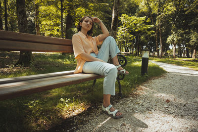 Full length of young woman sitting on bench