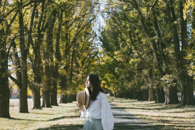 Woman standing by trees in forest