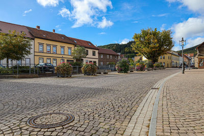 Houses by street in city against sky