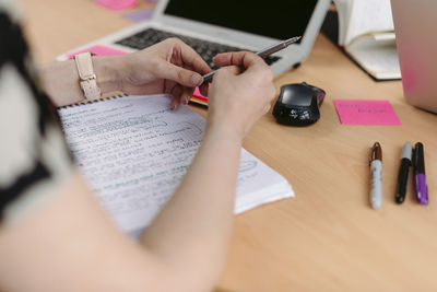 Midsection of woman reading book on table