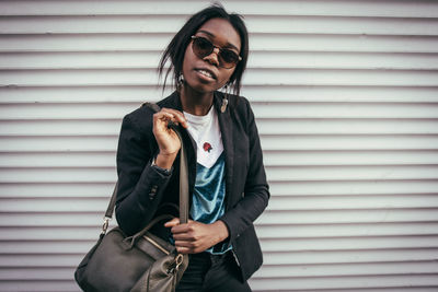 Portrait of young woman standing against wall