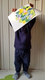 Boy holding paper while standing at home