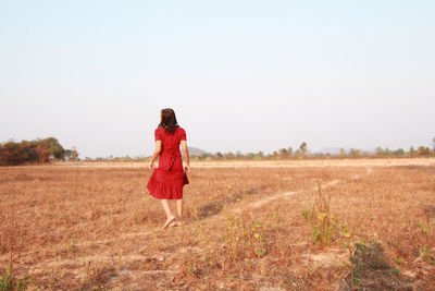 Rear view of woman walking on field