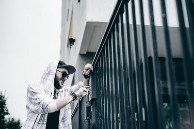 Low angle view of man entering password in security system on gate