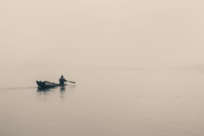 Man on boat in sea against sky