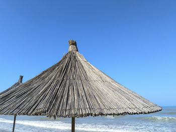 Traditional windmill on beach against clear blue sky