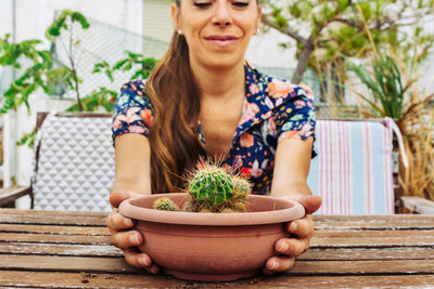 Young woman sitting by potted plant