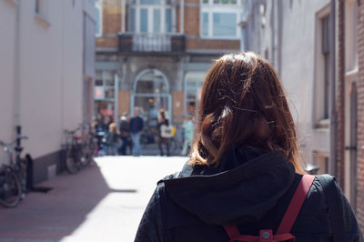 Rear view of young woman standing on street in city