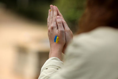 Stop war. peace in ukraine. woman hands with picture of flag of ukraine, hands folded in prayer.