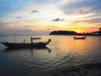 Boats in sea at sunset