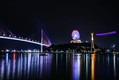 Illuminated bridge over river at night