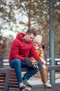 Portrait of smiling friends sitting on bench in park