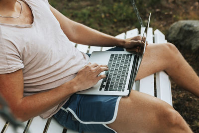 Man using laptop on bench swing