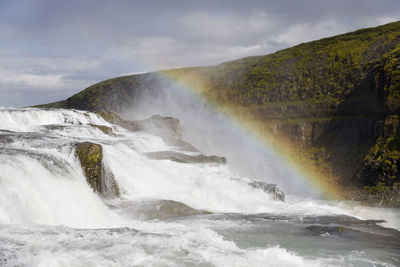 Scenic view of waterfall withbrainbow against sky