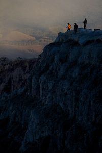 People on rock formations against sky