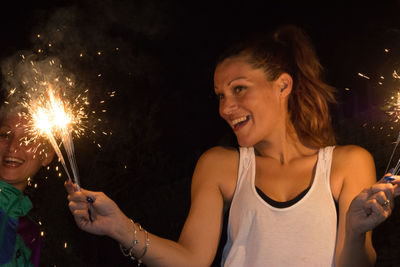 Close-up of young woman holding sparkler at night