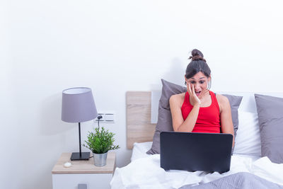 Side view of young woman using laptop at home