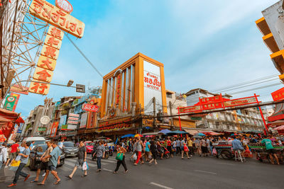 People walking on city street against sky