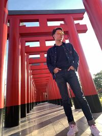 Portrait of young man standing against red wall