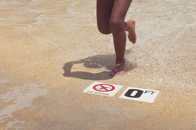 Low section of woman running on warning sign at poolside