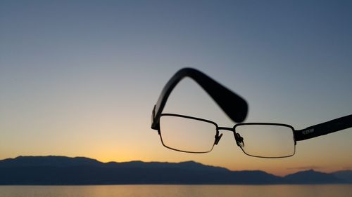 Close-up of silhouette against lake against sky during sunset