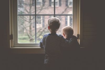 Two brothers looking through window