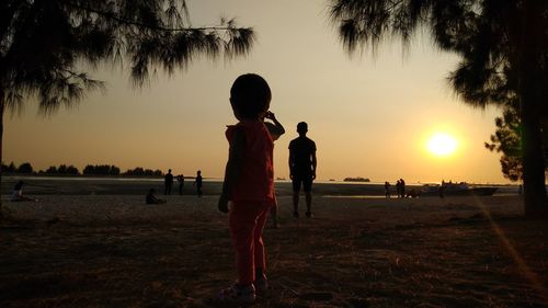 Silhouette people at beach against sky during sunset